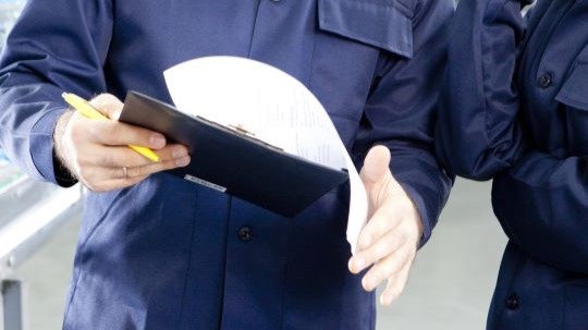 Two people talking while looking at a check sheet