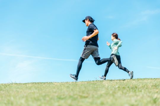 Men and women running under a blue sky