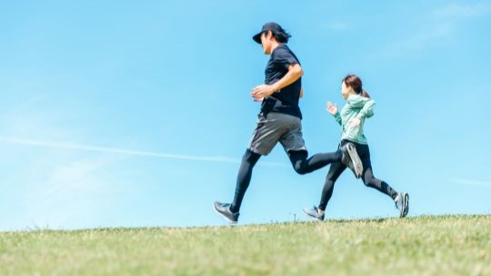 Men and women running under a blue sky