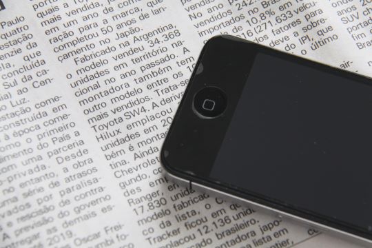 Smartphone placed on top of English newspaper