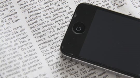 Smartphone placed on top of English newspaper