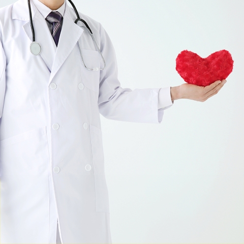 A man in a lab coat holding a red heart